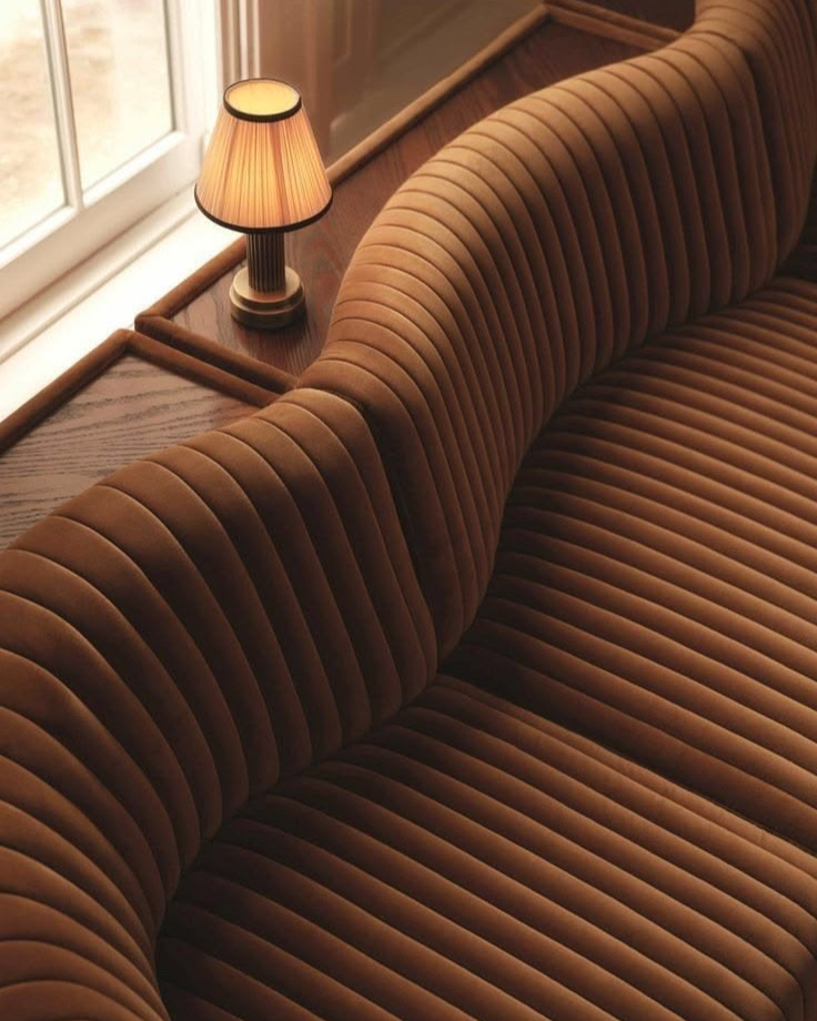 Banquette courbe en velours côtelé caramel et petite lampe plissée