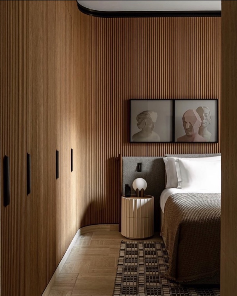 Chambre lambrissée, lit blanc et portraits encadrés