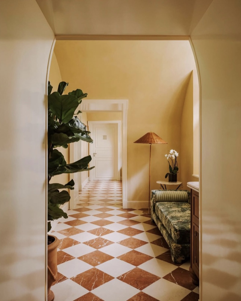 Couloir au sol en damier terracotta, banquette et palmier