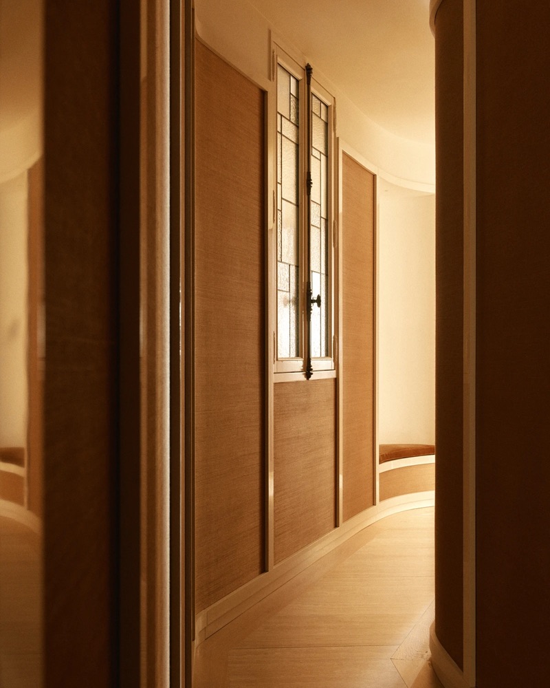 Couloir incurvé, panneaux de raphia et vitrail en meurtrière