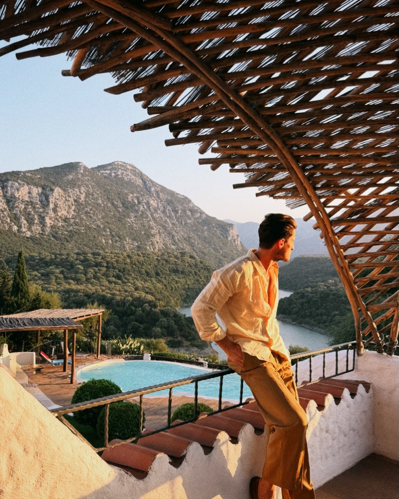 Terrasse sous une pergola de branches tressées, piscine et montagnes au couchant