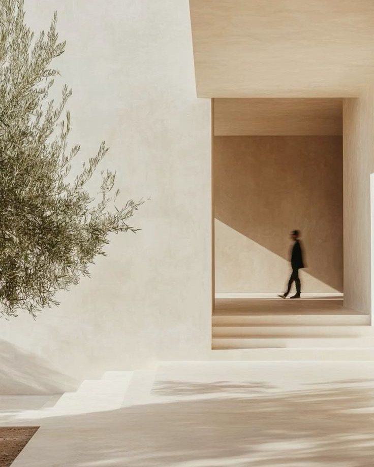 Portique d'enduit clair, olivier et silhouette traversant l'ombre
