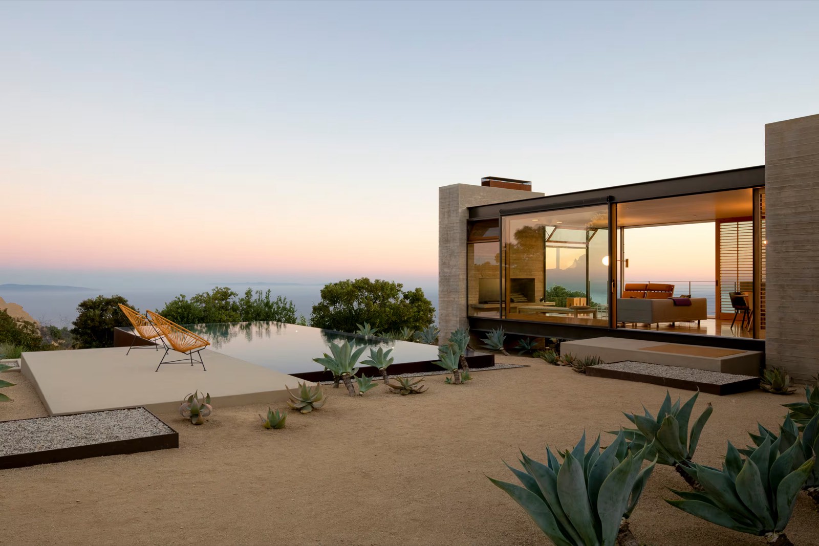 Villa de béton et de verre au couchant, piscine à débordement face à la mer