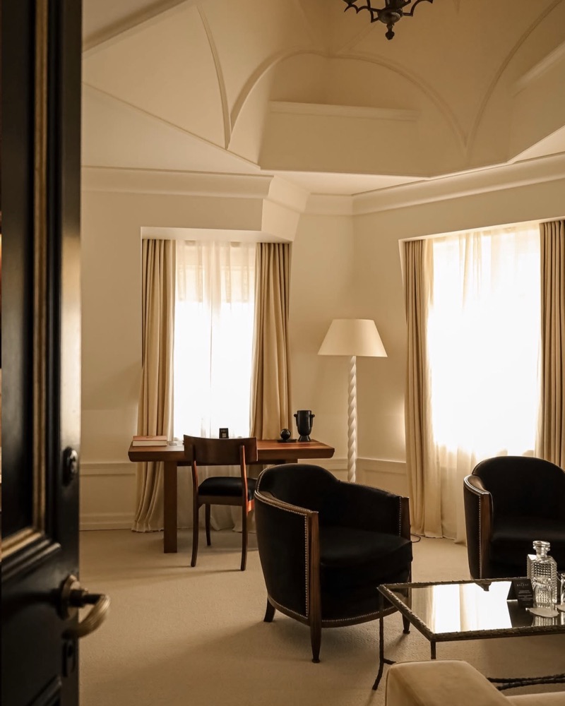 Suite parisienne, fauteuils sombres devant des fenêtres hautes